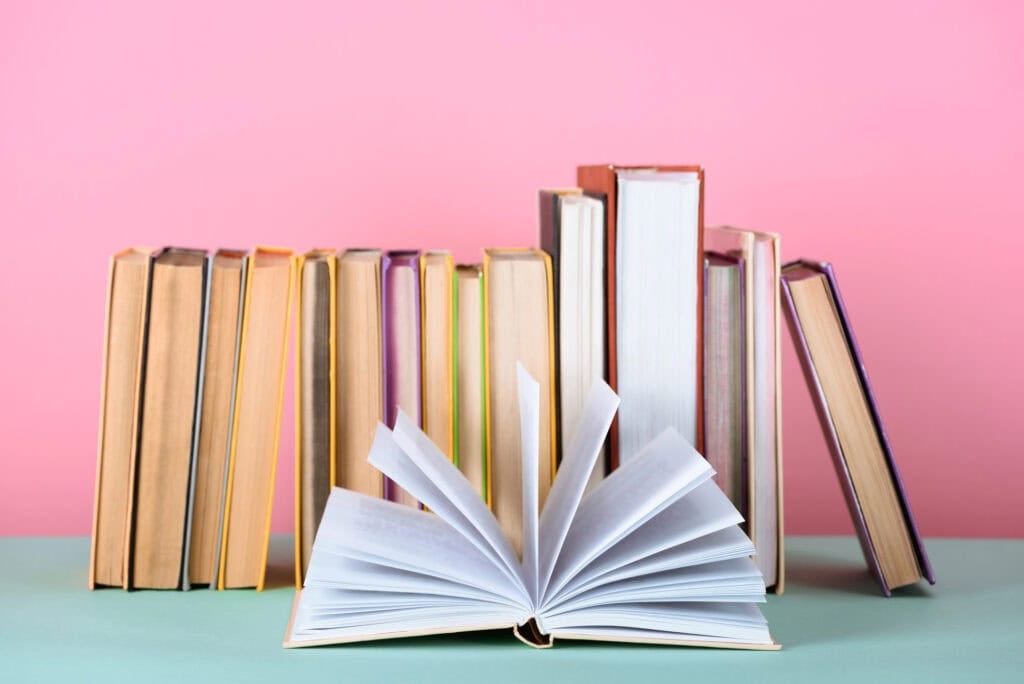 books on green table with pink background